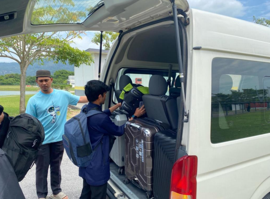 Pelajar menyusun bagasi ke dalam van institusi sebelum perjalanan.
