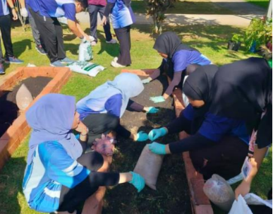 Peserta bekerjasama mengurus batas tanaman di Taman Herba.