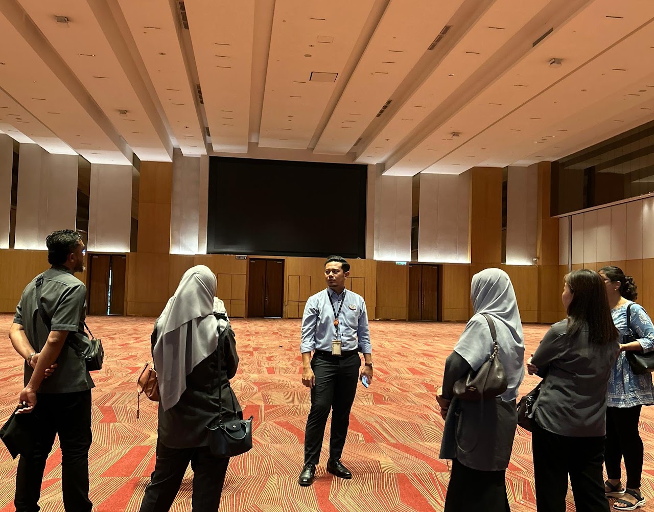 Delegasi mengikuti penerangan semasa lawatan tapak di ruang pusat konvensyen.